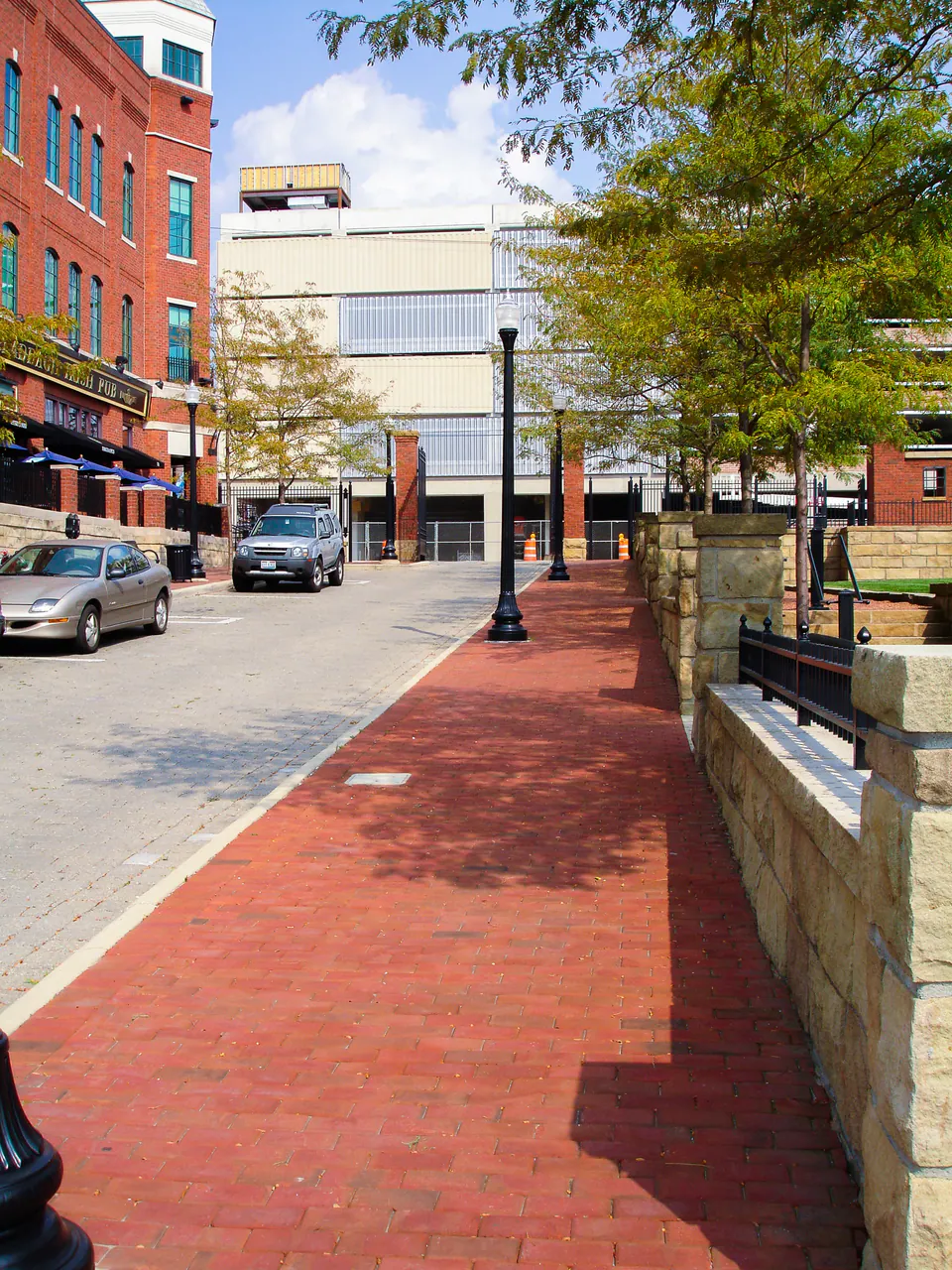 Peabody brick pedestrian walk with stone walls, site lighting, railings, trees, and urban buildings